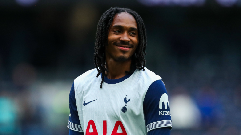 Djed Spence smiling in a Tottenham shirt.