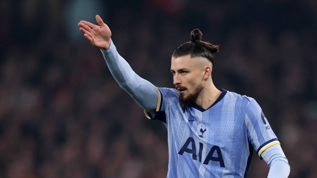 Tottenham defender Radu Dragusin stands with his arm raised during a game.