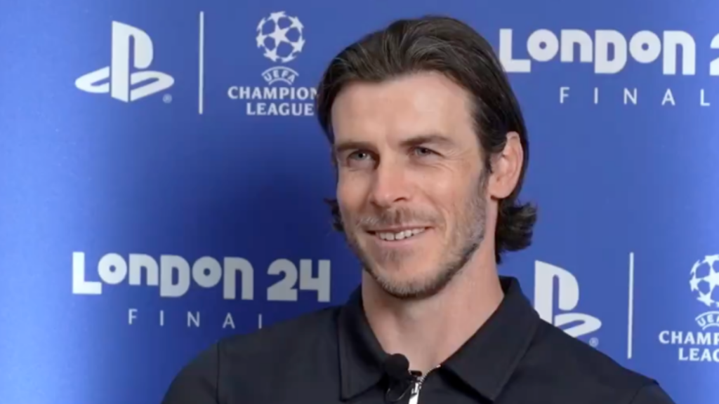 Former Tottenham star Gareth Bake smiles in front of a Champions League sponsorship board.
