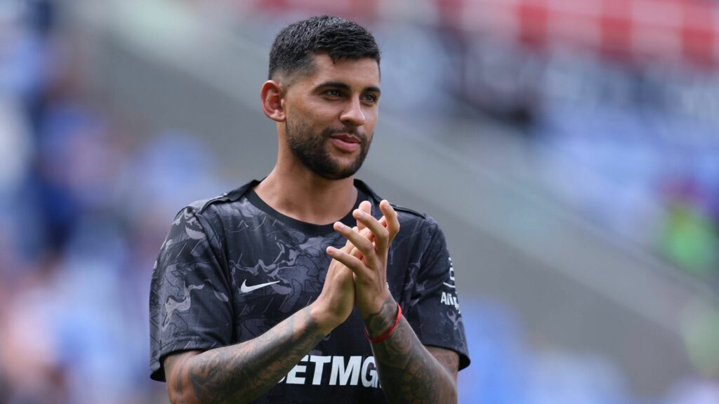 Cristian Romero claps Tottenham fans in front of a blurred background.