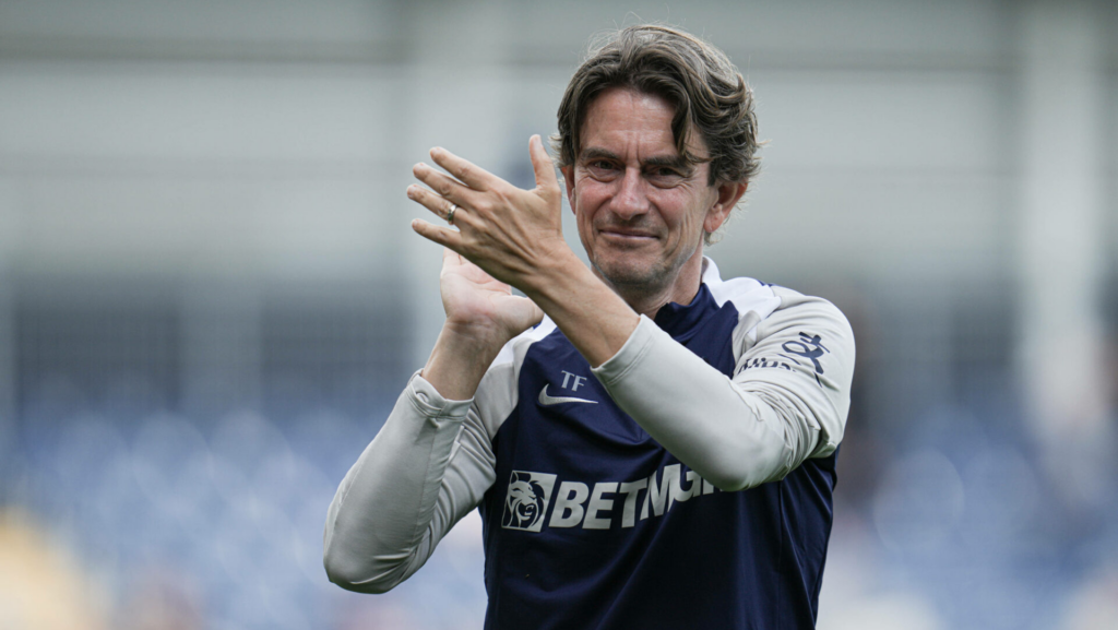 Tottenham manager Thomas Frank smiles and applauds.