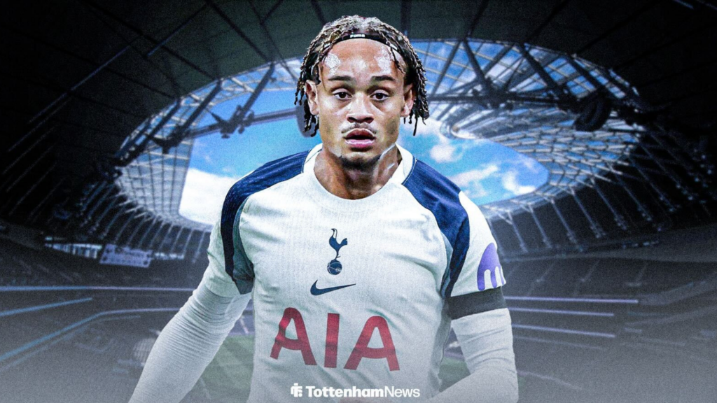 Xavi Simons wearing a Tottenham shirt in front of the Tottenham Hotspur Stadium.