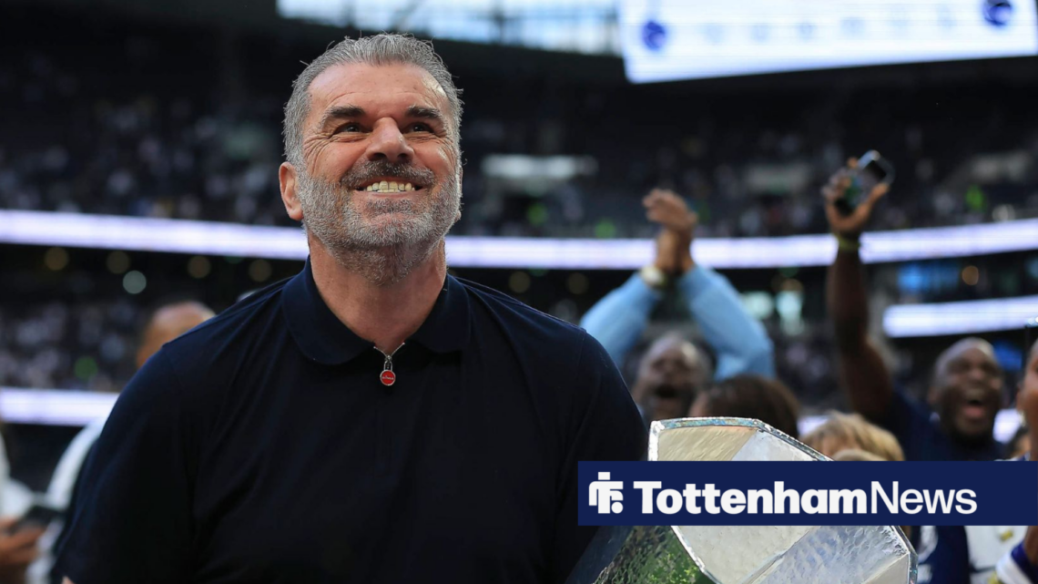 Ange Postecoglou grins while holding Europa League trophy.