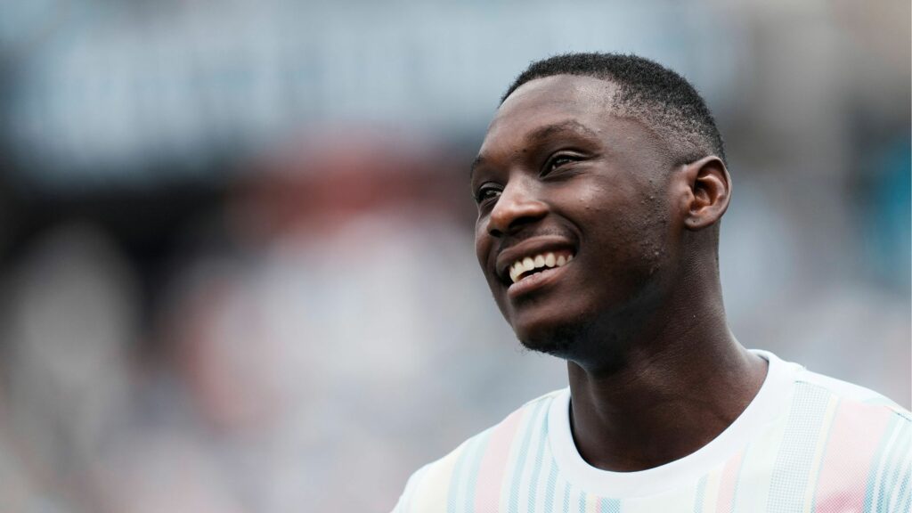Tottenham target Randal Kolo Muani smiles while wearing a white top